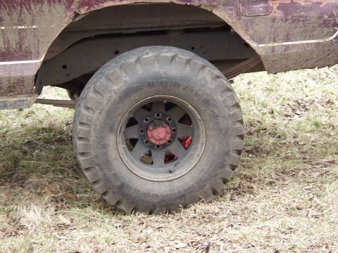 1979 Ford Bronco - Close-up of a large, knobby tire and the dirty fender of an off-road vehicle.