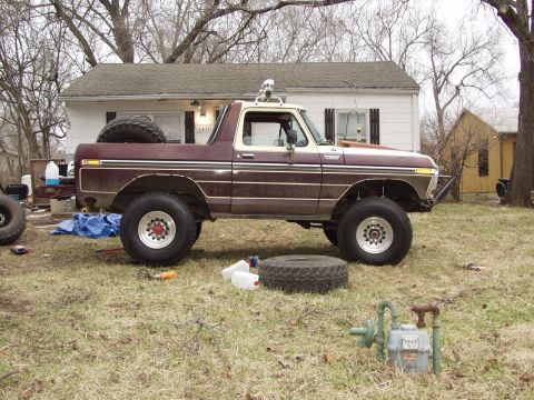 1979 Ford Bronco - A lifted Ford Bronco sits in a yard with a house in the background and a spare tire on its rear.