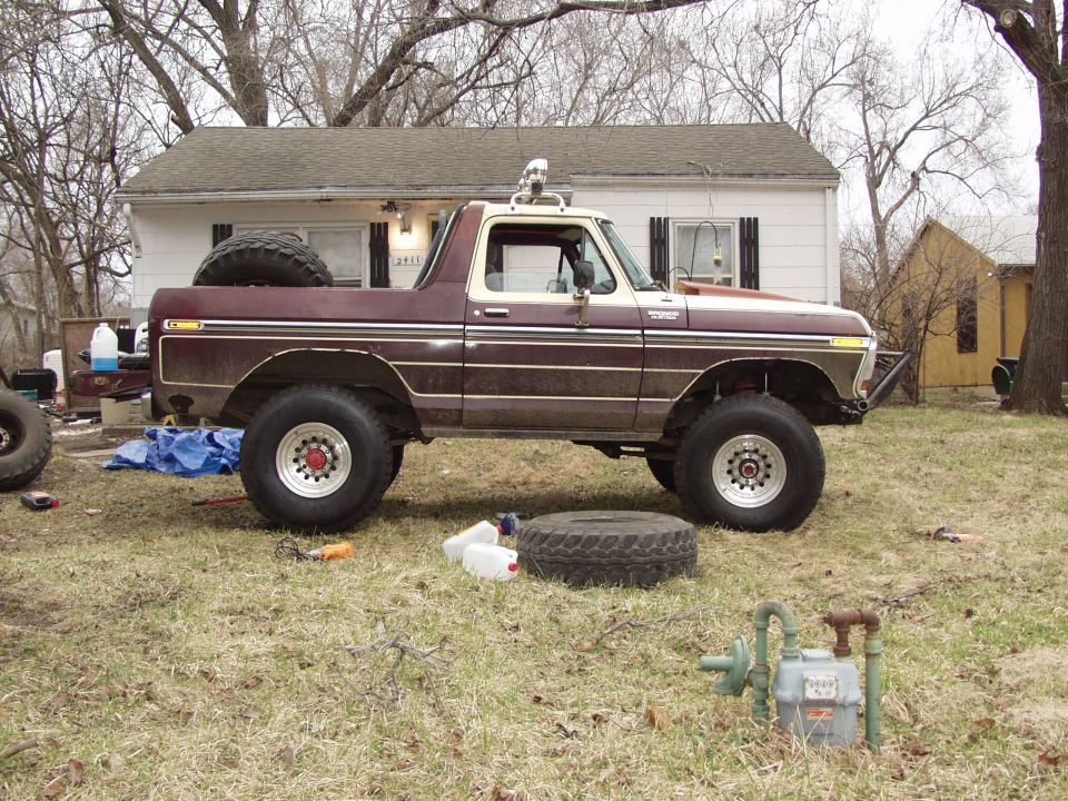 Lifted maroon and tan Ford Bronco, side view, parked in a yard