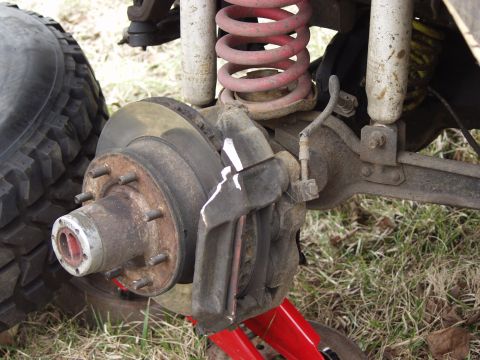 1979 Ford Bronco - Close-up view of a vehicle's front wheel brake assembly, including the rotor, caliper, and suspension components.