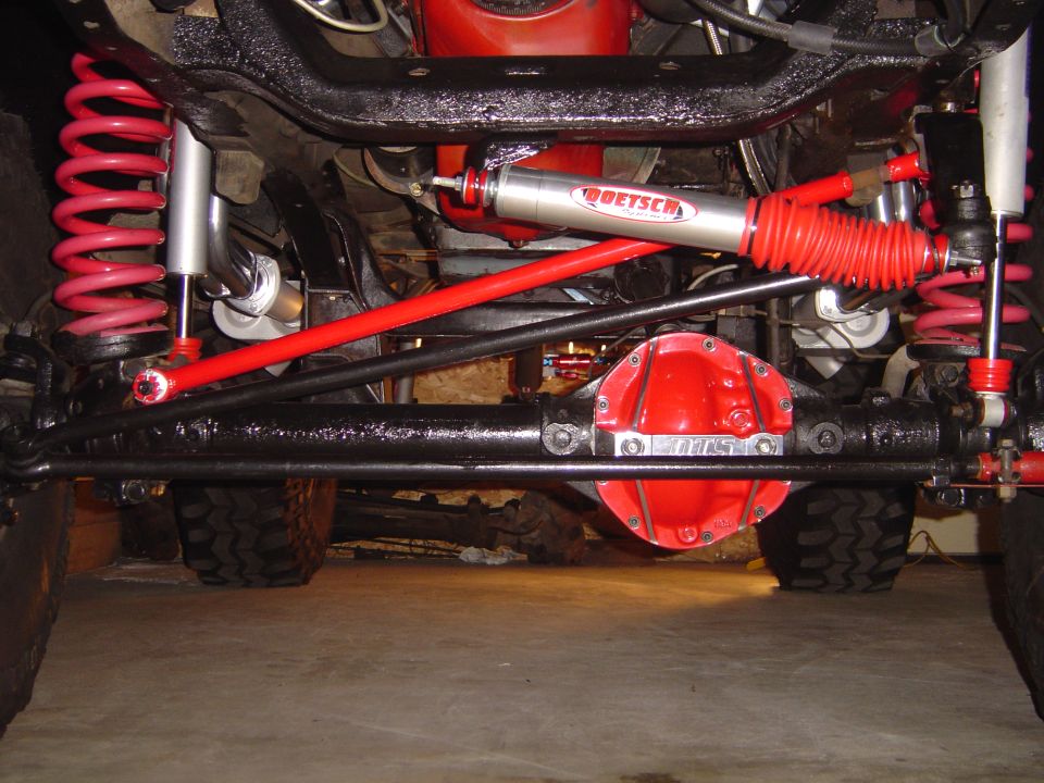 Solid front axle with red diff cover, red radius arms, coils and Doetsch steering stabilizer