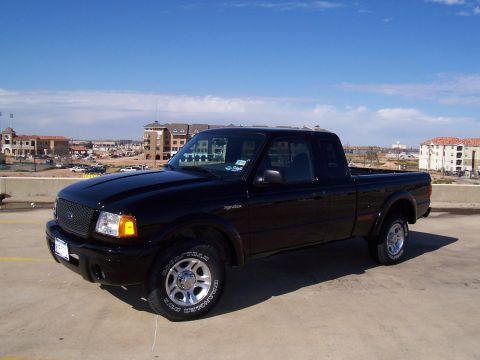 2003 Ford Ranger - A black 2003 Ford Ranger pickup truck is parked on a concrete surface under a blue sky with scattered clouds.
