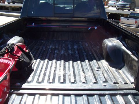 2003 Ford Ranger - The interior of a truck bed is shown, containing a red bucket and a duffel bag.