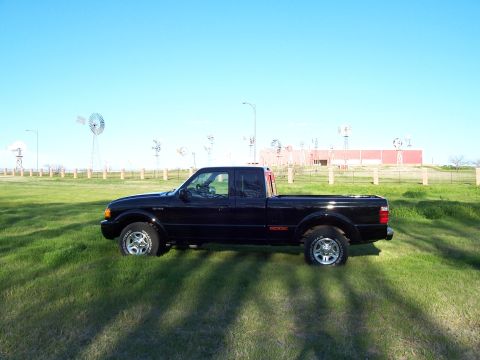2003 Ford Ranger - Side view of a black 2003 Ford Ranger pickup truck in a field with windmills.