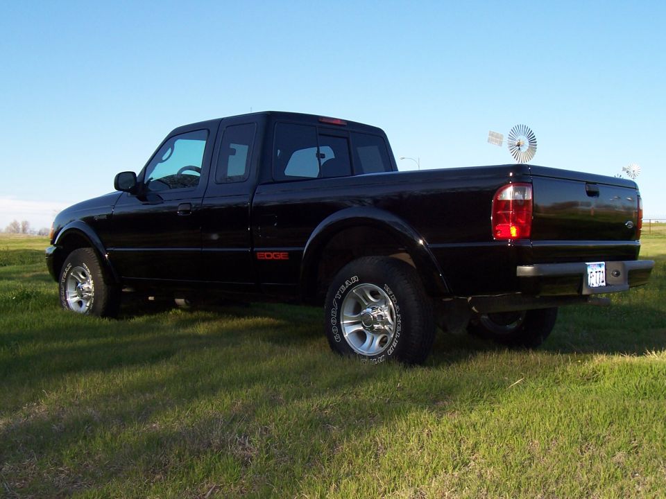 Black 2003 Ford Ranger Edge pickup truck parked in a grassy field with a windmill in the background