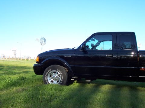 2003 Ford Ranger - A black 2003 Ford Ranger pickup truck is parked on a grassy field under a clear blue sky.
