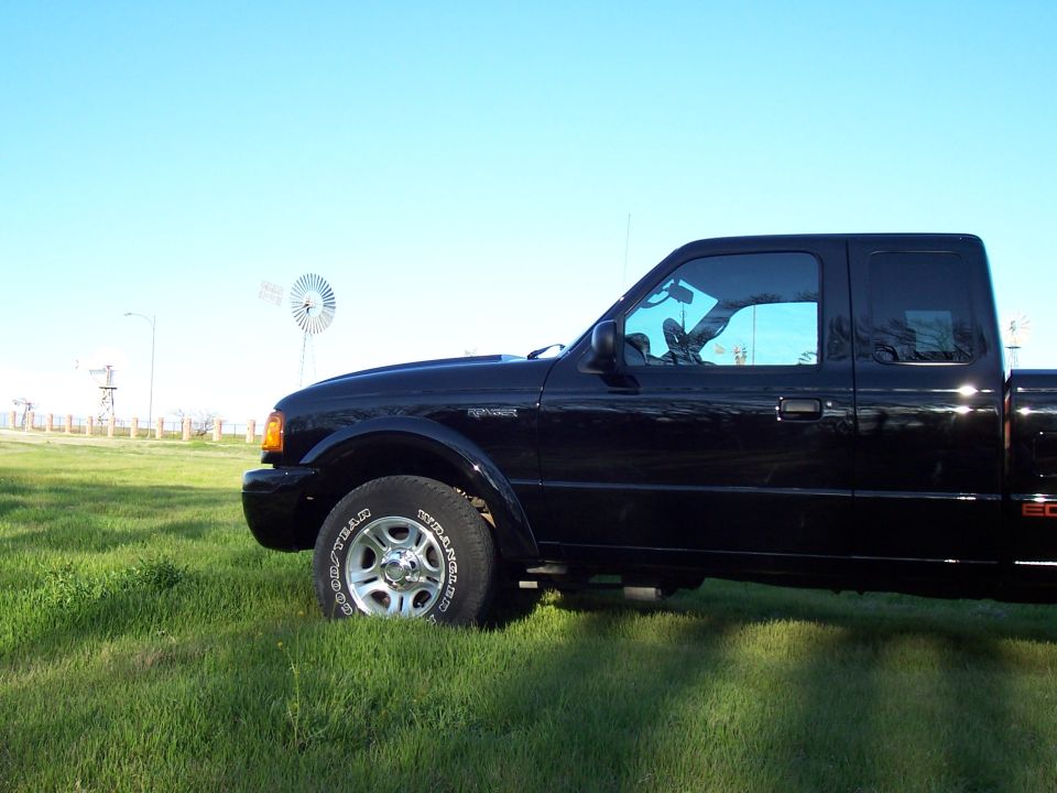 Black 2003 Ford Ranger pickup truck, side view, parked in grass with a windmill in the background