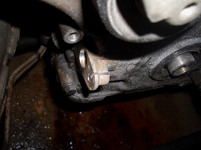 Close-up of a greasy engine component with bolts and metal brackets