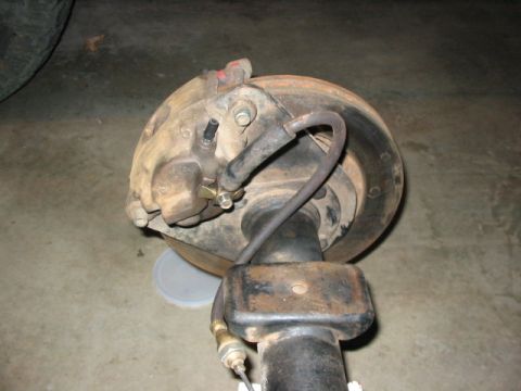 1995 Ford Bronco - This is a close-up view of a vehicle's brake system, focusing on the caliper and rotor assembly.