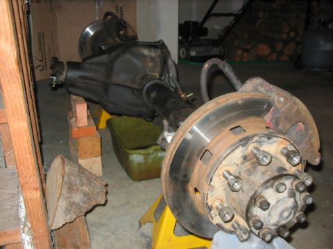 1995 Ford Bronco - A disassembled rear axle assembly, likely for a Ford Bronco, is supported by yellow jack stands in a garage.