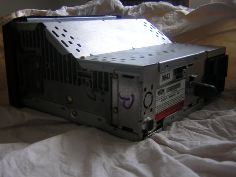 1998 Ford Crown Victoria - A car stereo unit, likely from a Ford or Lincoln vehicle, is shown from a side angle on a white cloth surface.