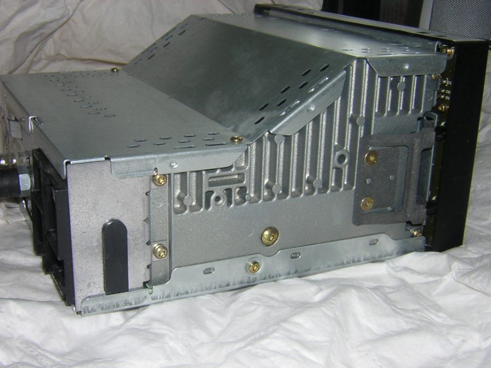 Side view of a car stereo chassis showing its finned metal casing on a white cloth