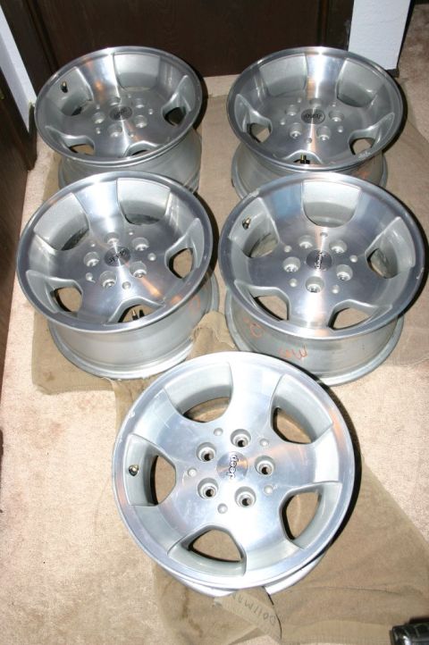 2003 Jeep TJ - Set of four aluminum Jeep wheels, each the brand's logo in the center cap.