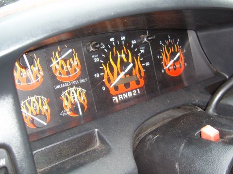 1993 Ford Bronco - Close-up of a Ford truck instrument cluster fitted with custom orange-and-yellow flame-graphic gauge faces across the speedometer, tachomet…