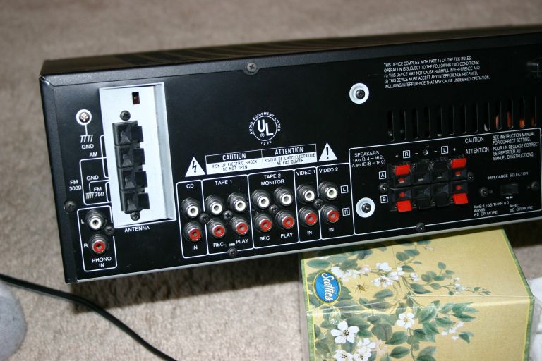 Rear panel of an audio receiver showing various input/output jacks and warning labels