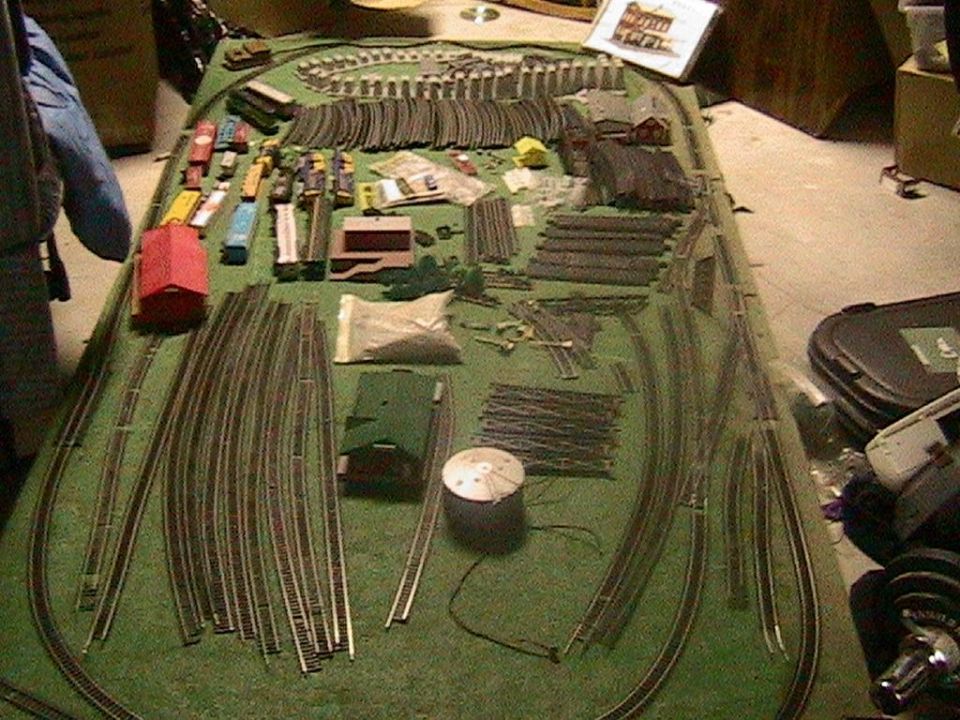 model train tracks, buildings, and cars laid out on a green surface