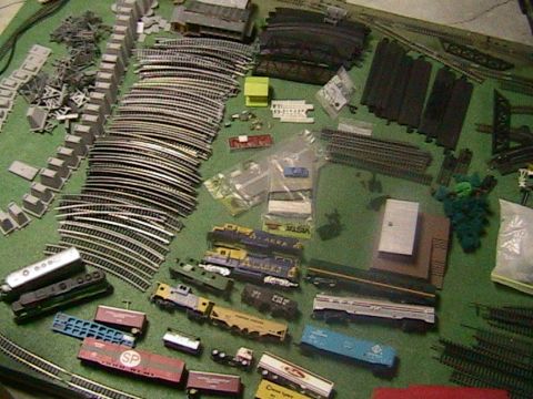 1981 Chevrolet C/K Pickup - A collection of model train tracks and rolling stock is spread out on a green surface.