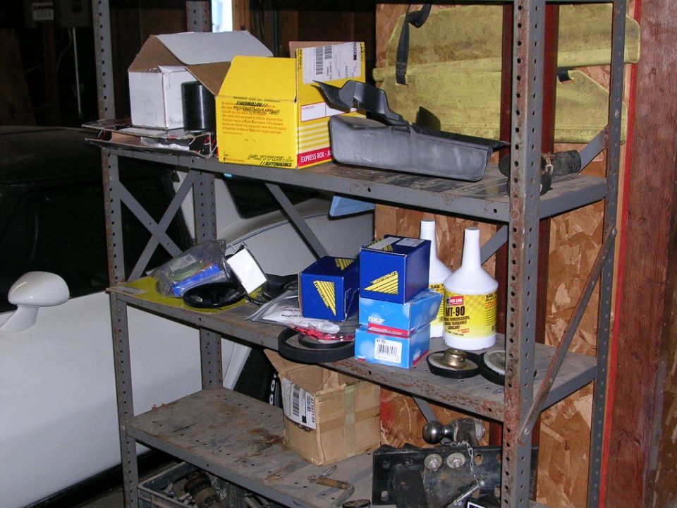 Garage shelf of parts including SKF bearings, Red Line MT-90 gear oil and a driveshaft