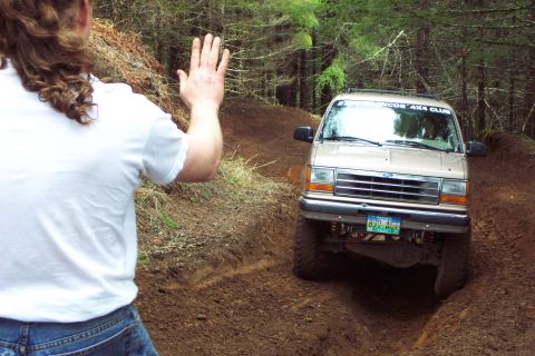 1994 Ford Explorer - A tan 1994 Ford Explorer navigates a rutted dirt trail, its windshield displaying a 'WOODS 4X4 CLUB' sticker.