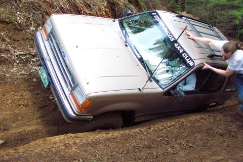 1994 Ford Explorer - A person helps push a 1994 Ford Explorer out of a ditch on a wooded trail.
