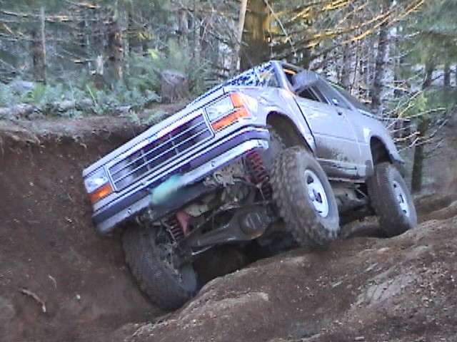 Silver Ford Explorer nosed down into a deep dirt gully on a forest off-road trail