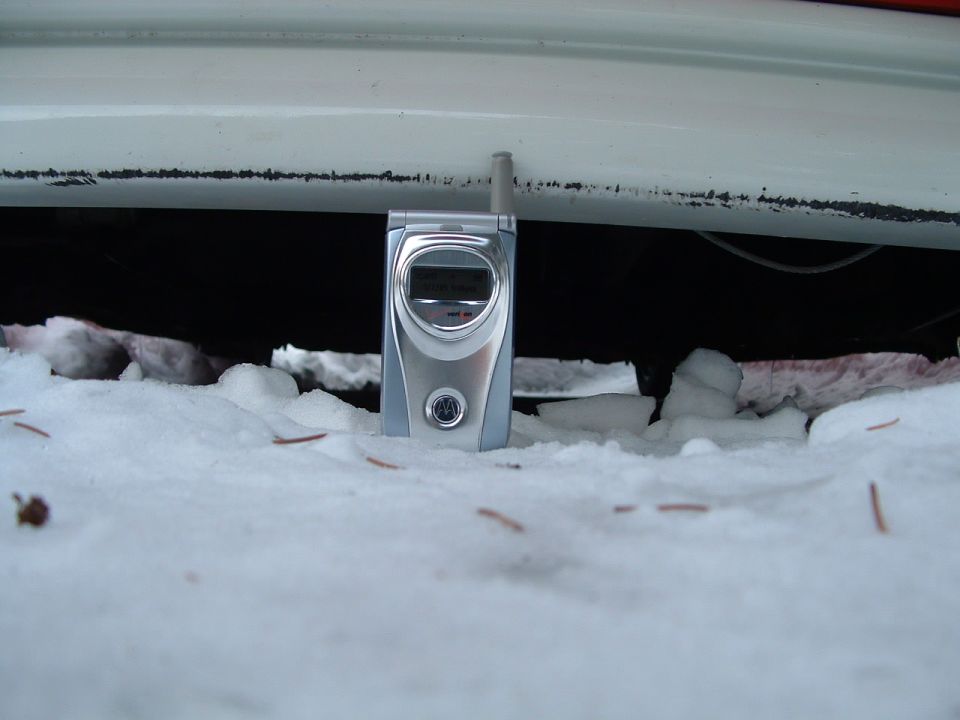 Flip phone stood in snow under rocker panel showing extremely low ride height