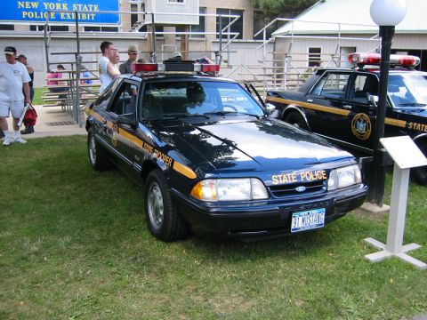 1991 Ford Mustang - A 1991 Ford Mustang SSP police car is displayed at a New York State Police exhibit, alongside another police vehicle.