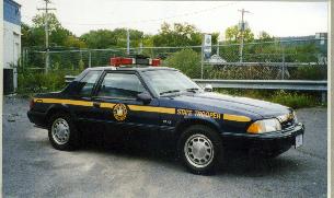 1991 Ford Mustang - Side view of a 1991 Ford Mustang SSP police car with emergency lights on the roof.