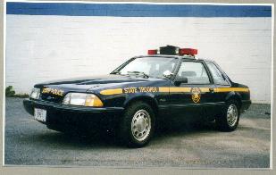 1991 Ford Mustang - A 1991 Ford Mustang SSP police car is parked in front of a white brick wall.