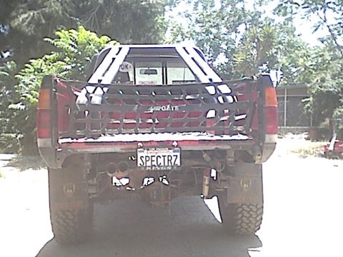 1991 Nissan Pathfinder - This Nissan pickup truck features a custom cargo net and dual exhaust pipes, with a license plate reading 'SPECTRZ'.