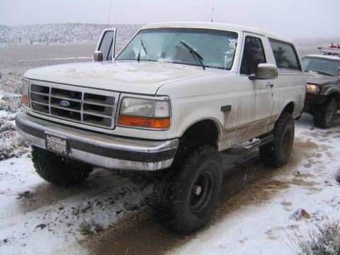 1993 Ford Bronco - A white Ford Bronco sits in a snowy landscape with its driver's door open.