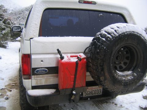 1993 Ford Bronco - A white Ford Bronco is parked in a snowy landscape, equipped with a spare tire and a red jerrycan on its rear.
