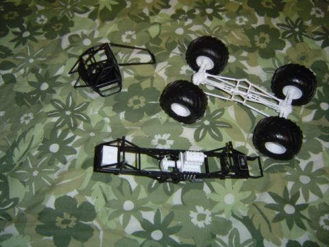 1979 Ford Bronco - Model kit parts for a monster truck are unassembled on a patterned background.