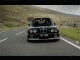 1990 Ford Probe - A black BMW M3 convertible is captured driving on a road with hills in the background.