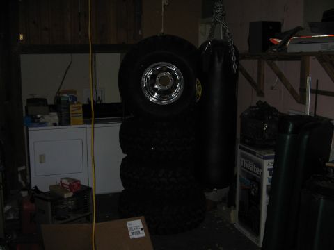 1978 Ford Bronco - A collection of tires and a punching bag are stored in a garage next to a washing machine and shelves.