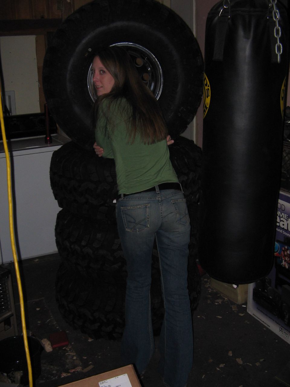 Woman leaning on a stack of large tires next to a punching bag