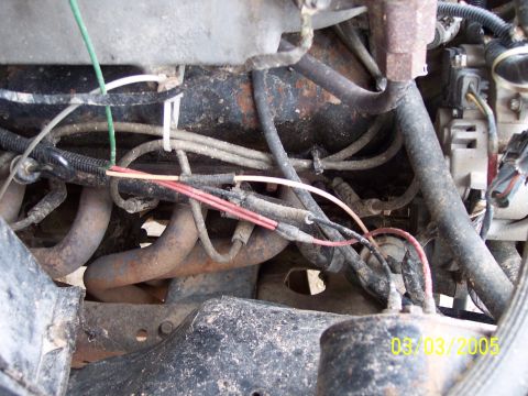 1987 Ford Bronco - This image shows a portion of a vehicle's engine compartment, focusing on wiring and exhaust components.