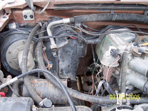 1987 Ford Bronco - A close-up view of a vehicle's engine compartment shows various hoses, wires, and mechanical components.