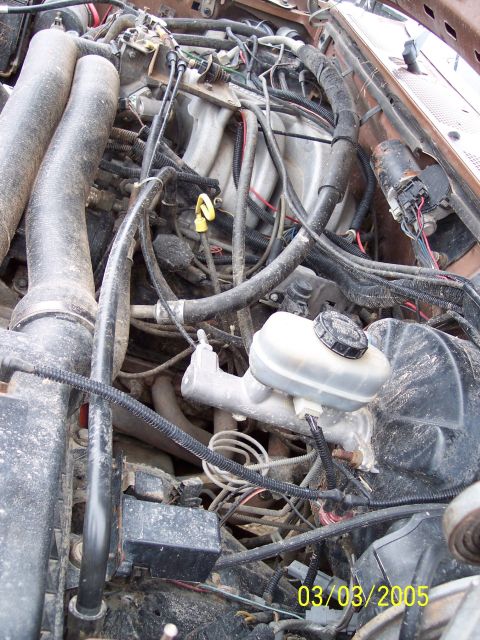 1987 Ford Bronco - Close-up view of a vehicle's engine compartment, showing the brake master cylinder and associated plumbing.