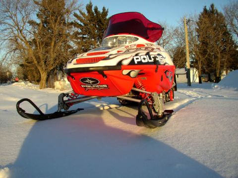 2003 Polaris 600 PRO X - A red and white Polaris snowmobile sits in a snowy landscape under a clear blue sky.