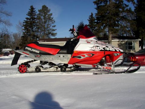 2003 Polaris 600 PRO X - Side view of a red and white 2003 Polaris 600 PRO X snowmobile with flame graphics.