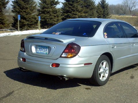 2002 Oldsmobile Aurora - The rear of a silver sedan is shown, a spoiler and dual exhaust pipes.