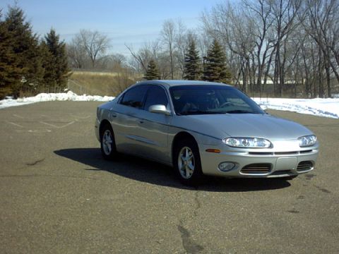2002 Oldsmobile Aurora - A silver 2002 Oldsmobile Aurora sedan is viewed from a three-quarter front angle in an outdoor parking lot.