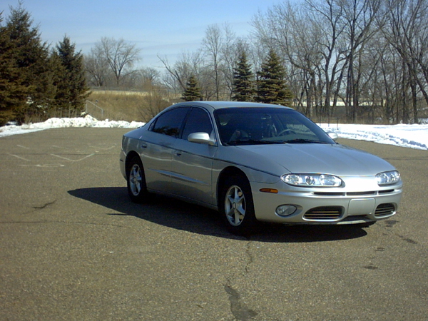 Silver 2002 Oldsmobile Aurora sedan parked on asphalt with snow in background