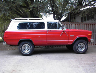 1993 Ford Bronco - Side view of a red and white Jeep Cherokee SJ with a white roof rack.