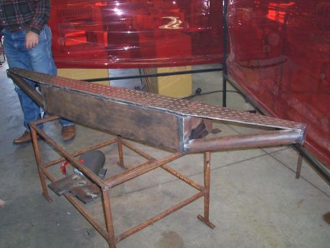 1989 Ford Bronco - A custom metal fabrication part, possibly a bumper or frame extension, is displayed on a metal stand.