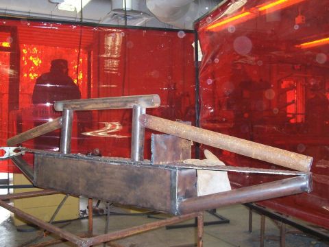 1989 Ford Bronco - Fabricated metal bumper assembly in a workshop setting with red welding screens.