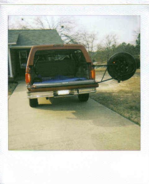 1995 Ford Bronco - Rear view of a brown Ford Bronco with its tailgate open and a spare tire mounted externally.