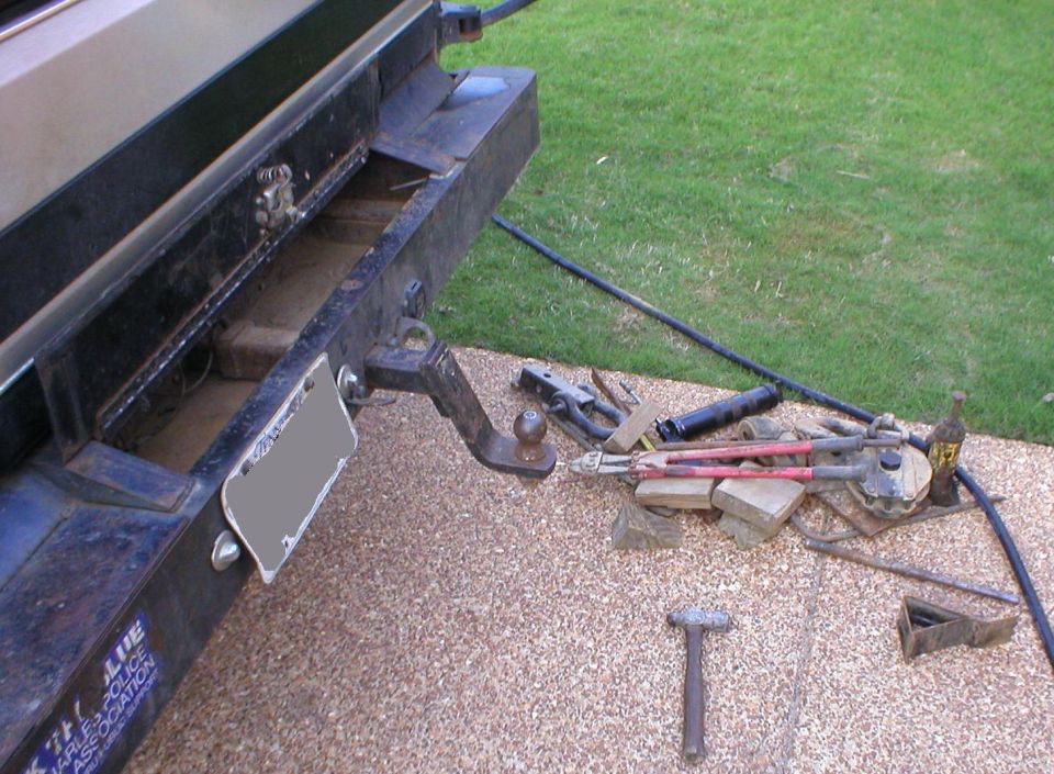 Truck rear receiver hitch with ball mount and scattered hand tools and chains on the ground
