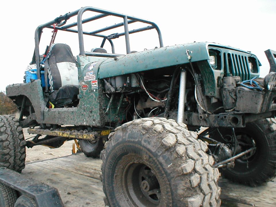 Muddy teal Jeep Wrangler trail rig with roll cage, stripped body and mud tires